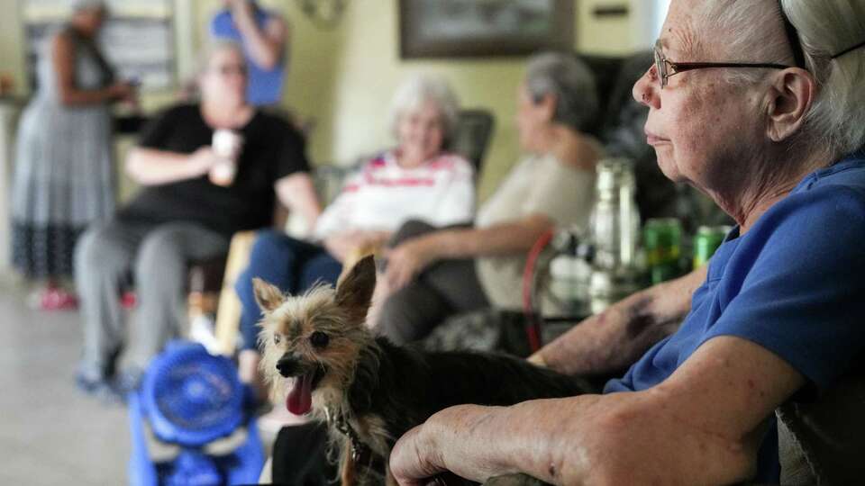 Joan Scheuermann and her 15-year-old dog Tilley sit in the lobby of a senior living apartment complex with other residents as they wait for the power to be restored in the aftermath of Hurricane Beryl on Wednesday, July 10, 2024, at the Timber Top apartments in Houston. She said she had to stay in the lobby because her apartment was too hot for her old dog. She and other residents in the lobby also praised the efforts of staff members at the complex during the aftermath of the storm. 