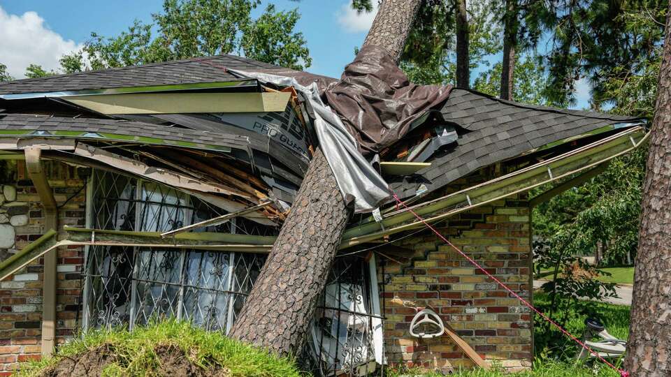 A fallen tree on the roof of a home in Meadowcreek Village, a community on their ninth day without power after Hurricane Beryl left thousands without power, is photographed on Tuesday, July 16, 2024, in Houston.