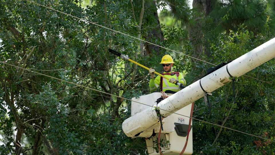 A worker with Davey Tree trims trees from utility lines along Champion Forest Tuesday, July 16, 2024, in Spring. Some of area is still without power after Hurricane Beryl.