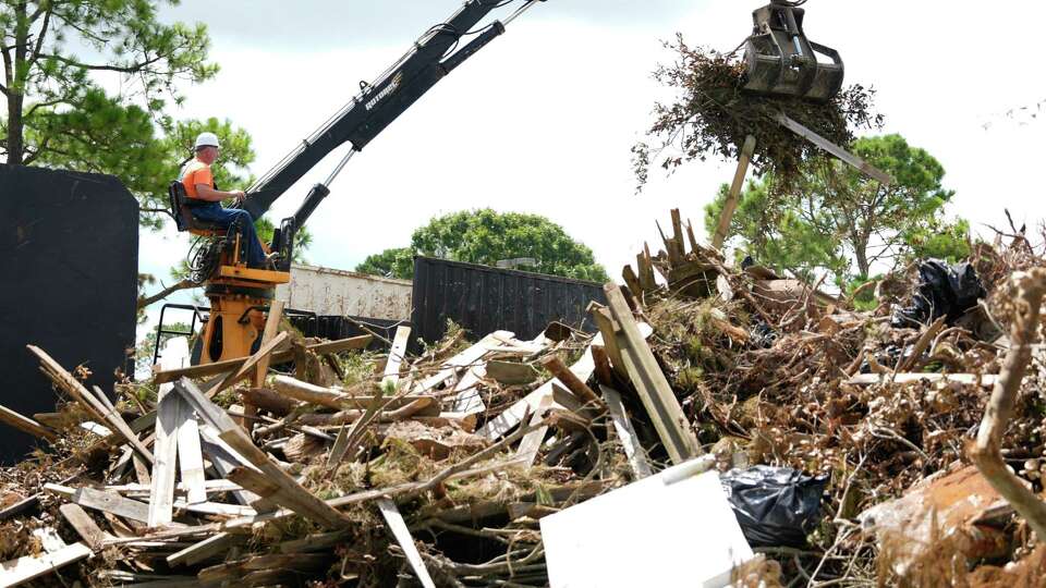 A man uses a crane to move debris into a large truck to be hauled away at a debris drop-off site at Lindsay/Lyons Park and Sports Complex, Wednesday, July 17, 2024, in Kingwood. The site was one of several for residents of Harris County Precinct 3 to drop off their debris after Hurricane Beryl.