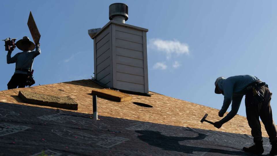 Roofers install tapping and inspect plywood on a new roof of a home damaged during Hurricane Beryl, Tuesday, July 16, 2024, in Kingwood.