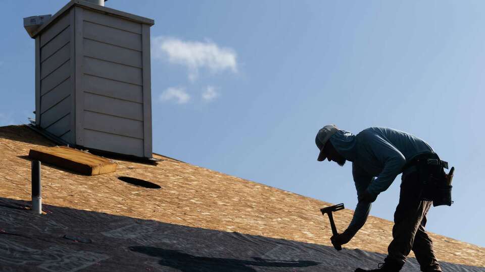 Roofers install tapping and inspect plywood on a new roof of a home damaged during Hurricane Beryl, Tuesday, July 16, 2024, in Kingwood.