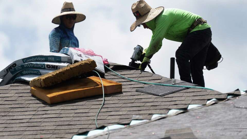 Roofers install shingles on a new roof of a home damaged during Hurricane Beryl, Tuesday, July 16, 2024, in Kingwood.