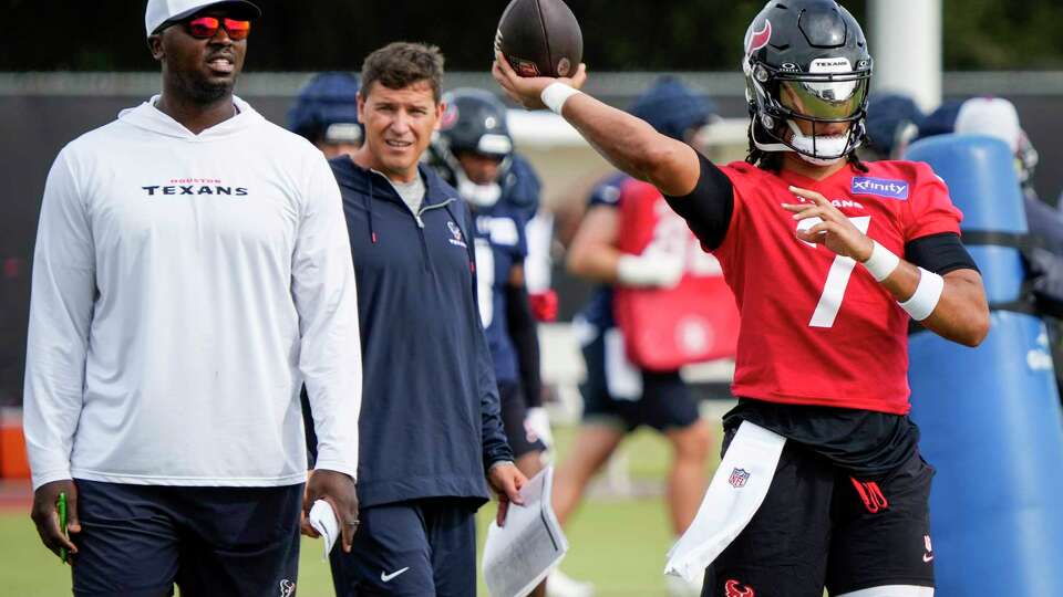 Houston Texans quarterbacks coach Jerrod Johnson looks on as quarterback C.J. Stroud (7) throws a ball during an NFL training camp Friday, July 19, 2024, in Houston.