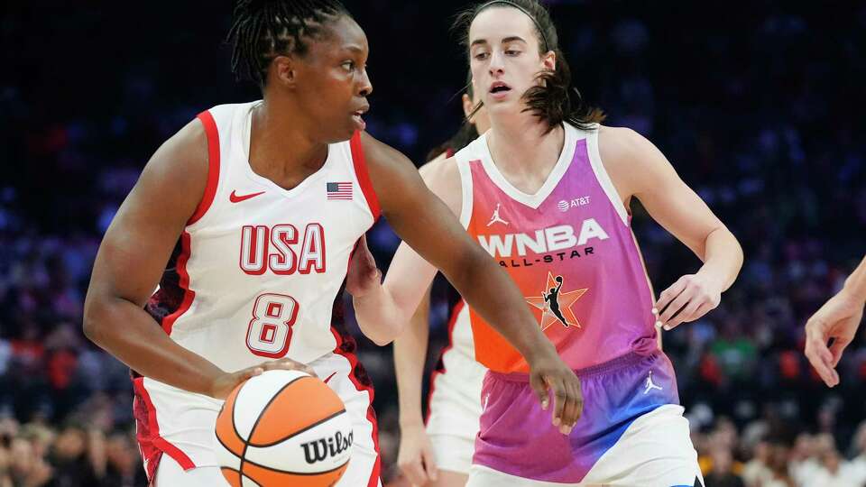 Chelsea Gray (8), of Team USA, dribbles the ball against Caitlin Clark, of Team WNBA, during the first half of a WNBA All-Star basketball game Saturday, July 20, 2024, in Phoenix. (AP Photo/Ross D. Franklin)