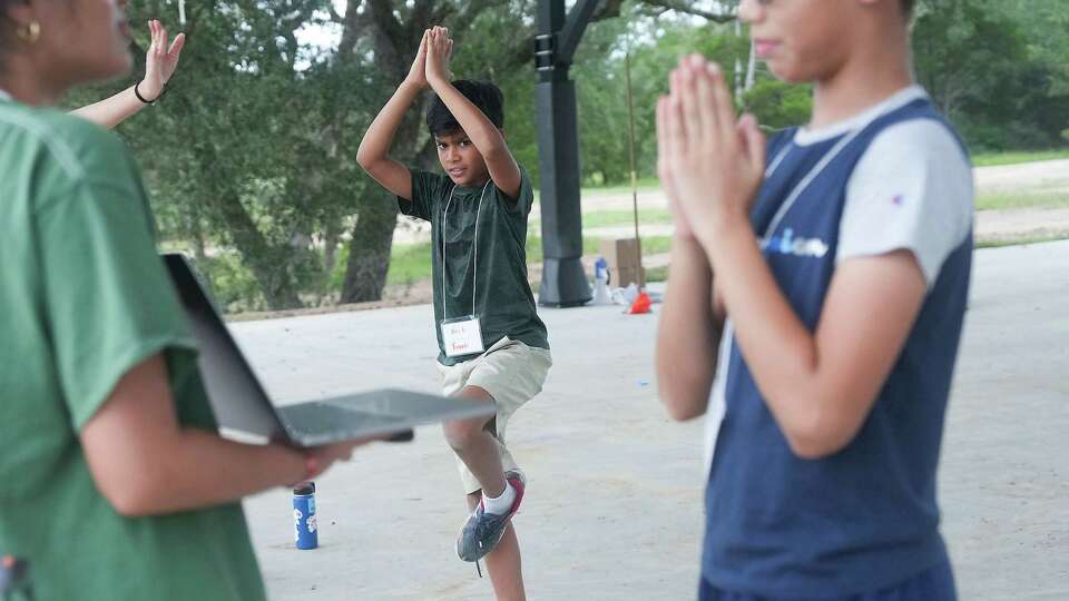 Neil Agrawal, 9, left, holds tree pose for 10 seconds as he eyes Kartik Rajaia recite the Gayatri Mantra during a relay race at Hindu Heritage Camp on Wednesday, July 24, 2024 in Columbus.