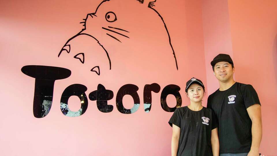 Owners Alan Liang, and his wife Jennie Wang next to the Totoro logo inside of Totoro Mochi Donut on Thursday, July 25, 2024, in Friendswood.