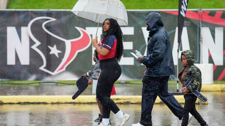 Houston Texans fans walk through the rain as they make their way to watch practice during an NFL training camp Saturday, July 27, 2024, in Houston.