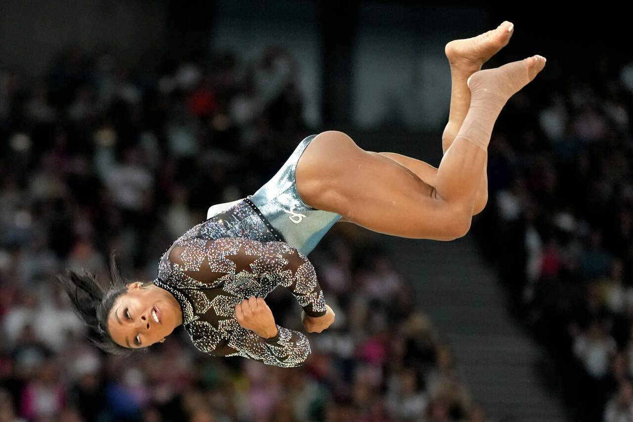 With her left calf wrapped, Simone Biles competes in floor exercise in team and all-around qualifying on Sunday.