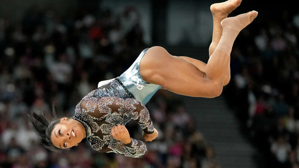 With her left calf wrapped, Simone Biles competes in floor exercise in team and all-around qualifying on Sunday.