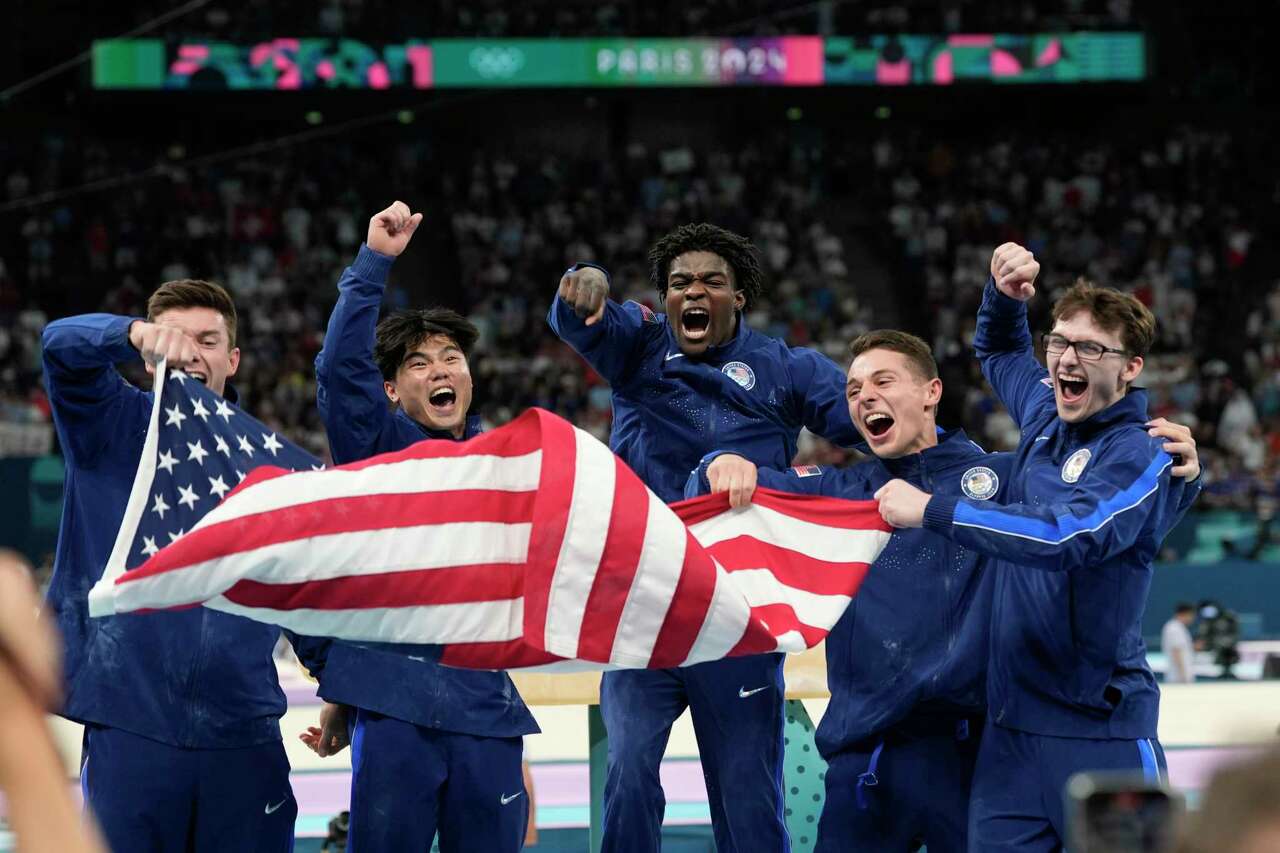 Team USA from left to right Brody Malone, Asher Hong, Fred Richard, Paul Juda and Stephen Nedoroscik, of the United States, celebrate after winning the bronze medal during the men's artistic gymnastics team finals round at Bercy Arena at the 2024 Summer Olympics, Monday, July 29, 2024, in Paris, France. (AP Photo/Abbie Parr)