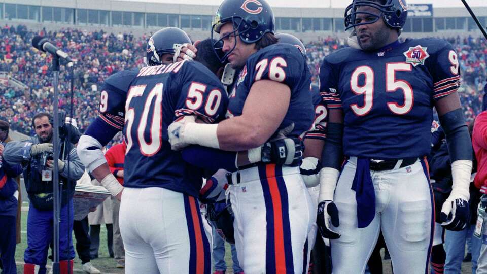 FILE - Chicago Bears nine-time Pro Bowler Mike Singletary (50) gets a bear hug from teammate Steve McMichael (76) prior to an NFL football game against the Pittsburgh Steelers in Chicago, Dec. 13, 1992. McMichael will be inducted into the Pro Football Hall of Fame Saturday, Aug. 3, 2024. (AP Photo/David Boe, File)