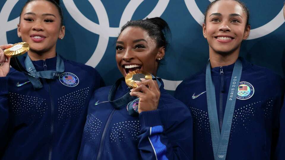 From left to right, Suni Lee, Simone Biles, Hezly Rivera celebrate after winning the gold medal during the women's artistic gymnastics team finals round at Bercy Arena at the 2024 Summer Olympics, Tuesday, July 30, 2024, in Paris, France. (AP Photo/Charlie Riedel)