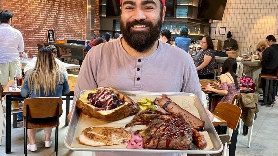 Houston food influencer Shawn Singh holding a plate of barbecue. 