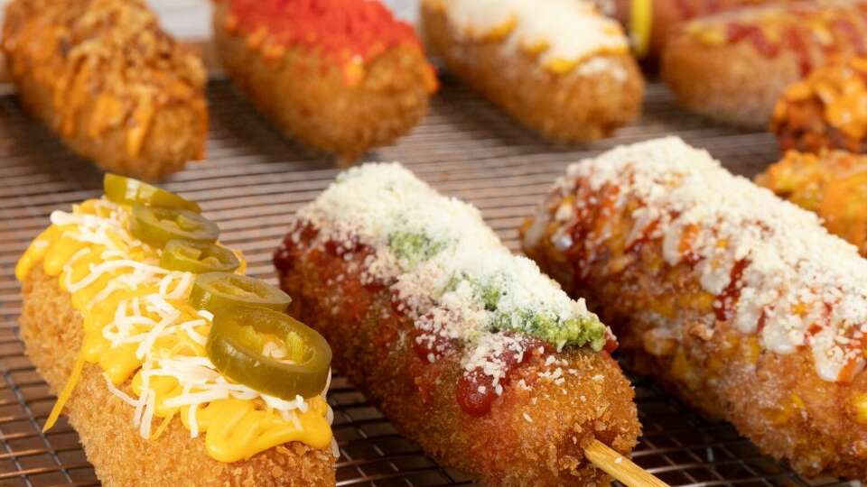 Korean corn dogs, a popular street food, are made with a rice flour batter and coated in Panko breadcrumbs. They are served with a variety of toppings. 