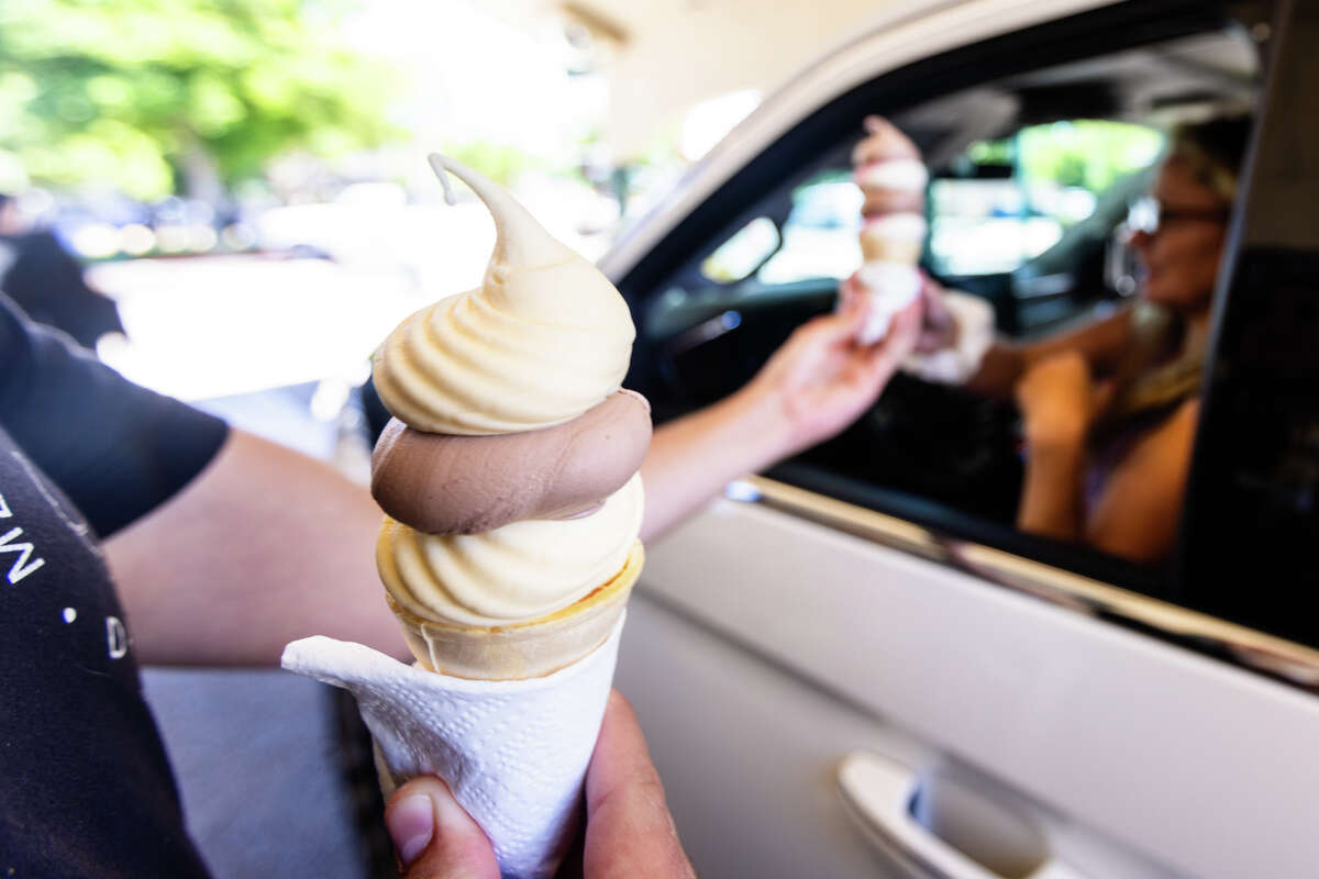 An employee hands ice cream cones to Cynthia Selinger at Meadowlark Dairy in Pleasanton, Calif. on July 31, 2024.