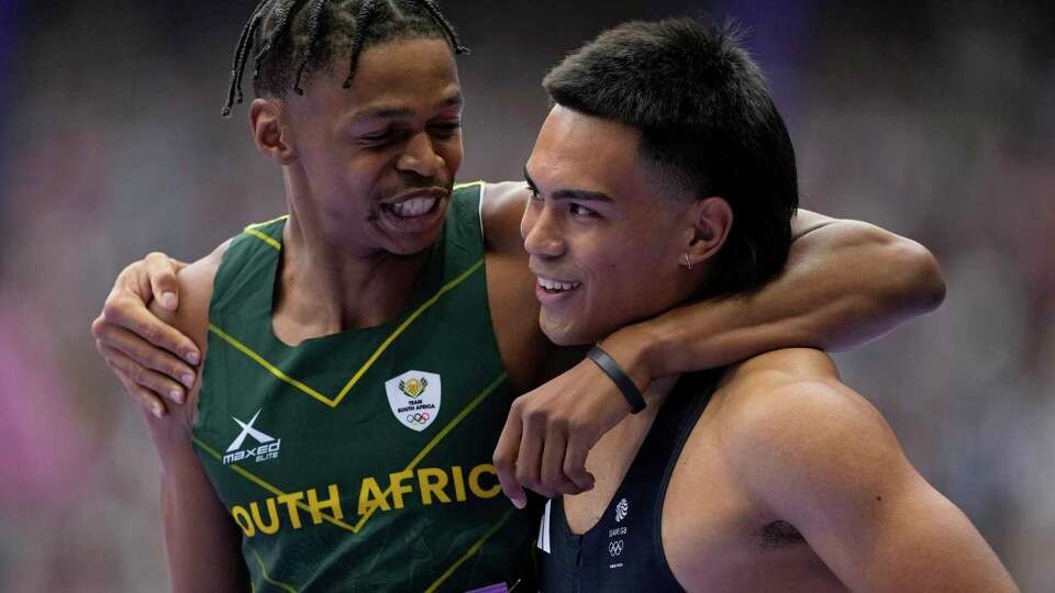 Shaun Maswanganyi, of South Africa, left, and Louie Hinchliffe, of Britain, react after qualifying in a men's 100 meters round 1 heat at the 2024 Summer Olympics, Saturday, Aug. 3, 2024, in Saint-Denis, France. (AP Photo/Ashley Landis)