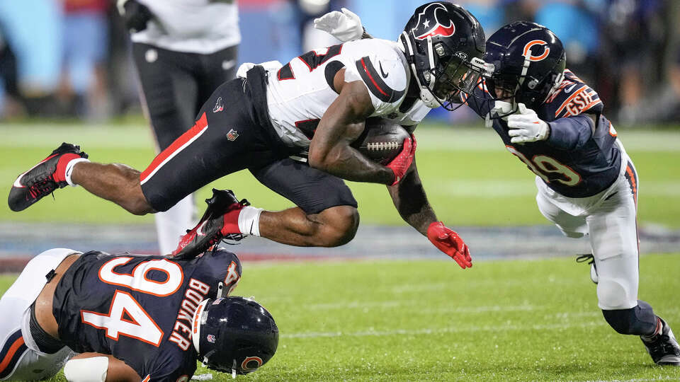 Houston Texans running back Cam Akers (22) is brought down by Chicago Bears defensive lineman Austin Booker (94) and cornerback Josh Blackwell (39) during the first half of the Hall of Fame Game on Thursday, Aug. 1, 2024 in Canton, Ohio.