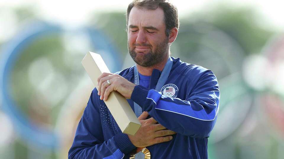 Gold medalist Scottie Scheffler of Team United States reacts on the podium during the Men's Individual Stroke Play medal ceremony following Day Four of the Men's Individual Stroke Play on day nine of the Olympic Games Paris 2024 at Le Golf National on Sunday, Aug. 4, 2024, in Paris.