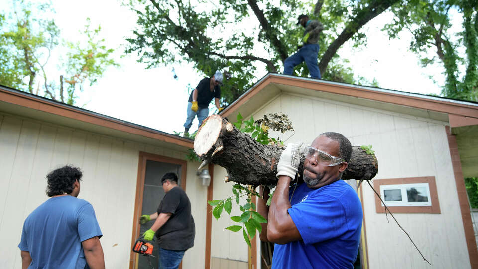 Wallace Ervin with Pipe Fitters Local Union 211 carries a cut piece of a pecan tree as he and other union member volunteers work to clear Hurricane Beryl debris from the East Aldine home of Lynn Williams Tuesday, July 16, 2024, in Houston.