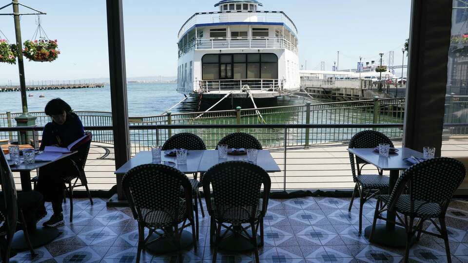 Tables set for dining in the outdoor dining area is seen with a view of the bay at Alora on Tuesday, April 9, 2024 in San Francisco, Calif.