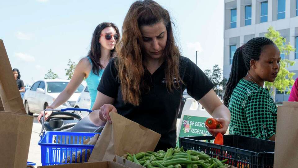 Zainab Mohammed selects fresh red peppers from the produce sourced from local growers and made available at the Urban Harvest Mobile Market Thursday, Aug. 8. 2024 near HOPE Clinic - Alief Community Health Center.