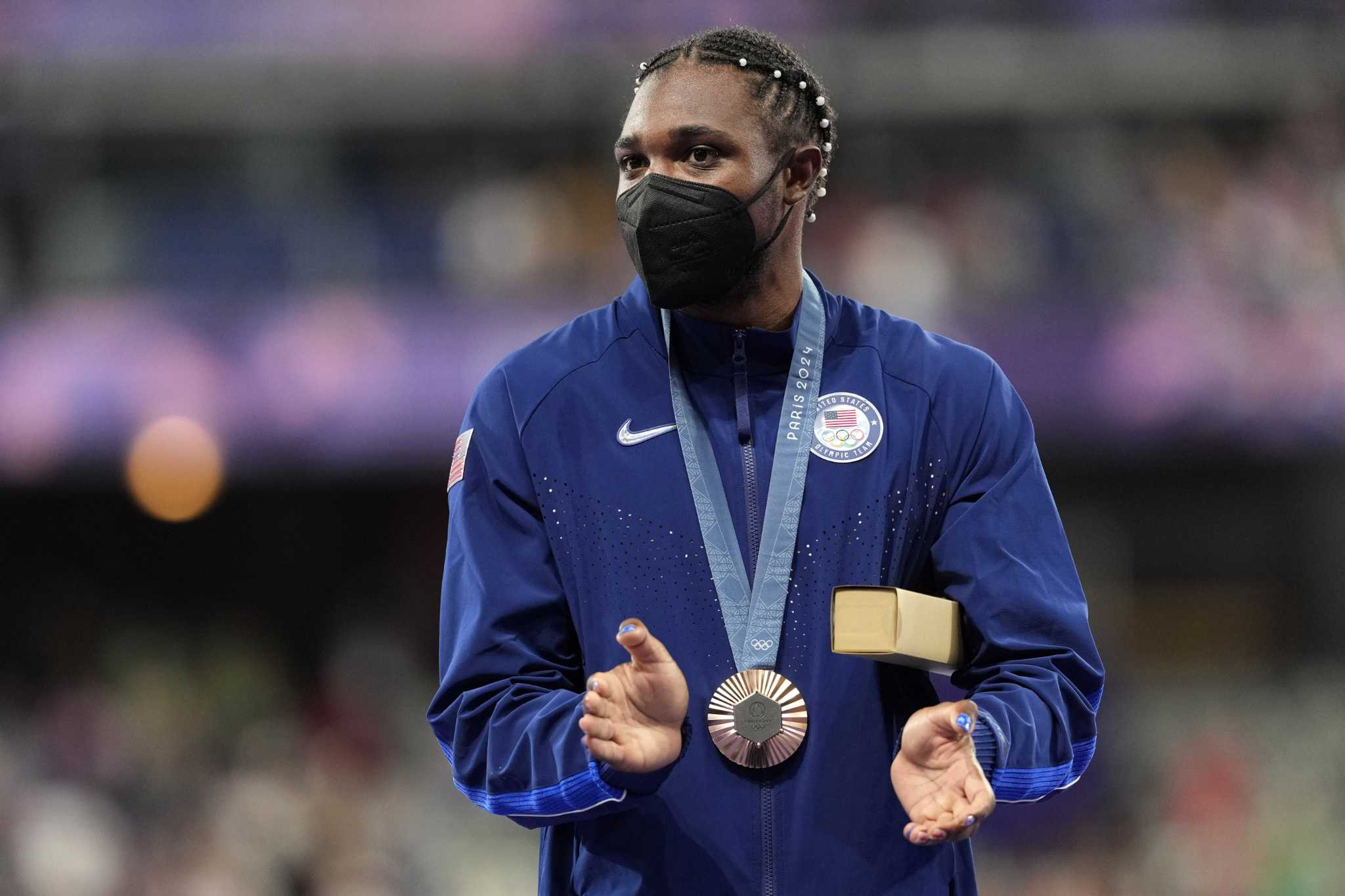 A masked Noah Lyles accepts his bronze medal in the 200meter final