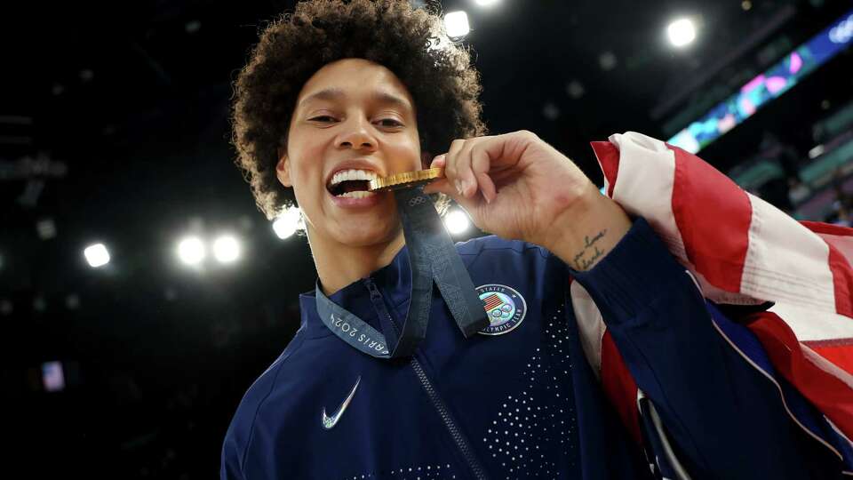 PARIS, FRANCE - AUGUST 11: Gold medalist Brittney Griner of Team United States bites her medal during the Women's basketball medal ceremony on day sixteen of the Olympic Games Paris 2024 at Bercy Arena on August 11, 2024 in Paris, France.