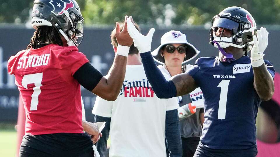 Houston Texans quarterback C.J. Stroud (7) and wide receiver Stefon Diggs (1) raise their arms as the start running drills during an NFL training camp Sunday, Aug. 11, 2024, in Houston.