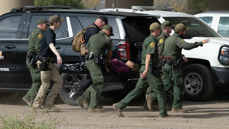 Border Patrol agents carry a migrant on a stretcher from the outdoor detention area in Eagle Pass.