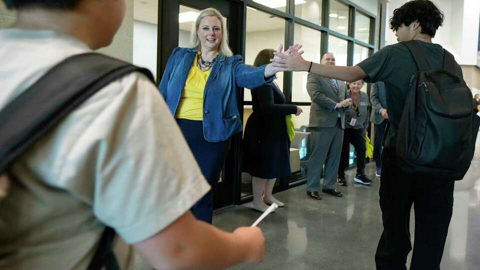 Principal Kara Morgan high fives students as they arrive for the first day of school at Nelson Junior High in Katy Independent School District on Wednesday, Aug. 14, 2024 in Katy. The Nelson faculty and staff welcomed 904 students to the new school.