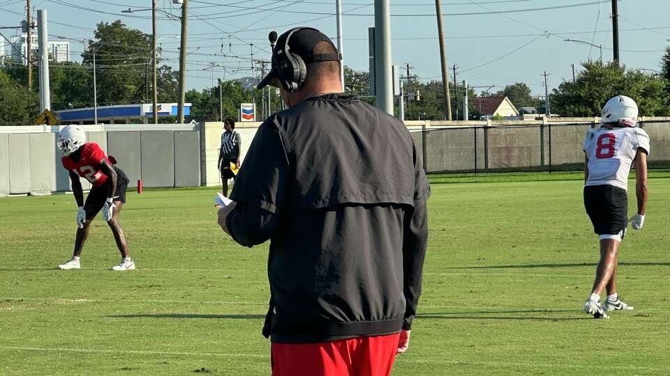 UH quarterbacks coach Shawn Bell wearing headsets during practice.