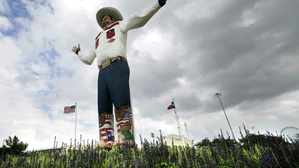 FILE - Bluebonnets, the state flower of Texas, surround Big Tex as storm clouds move in above, Friday, Sept. 27, 2013, in Dallas.