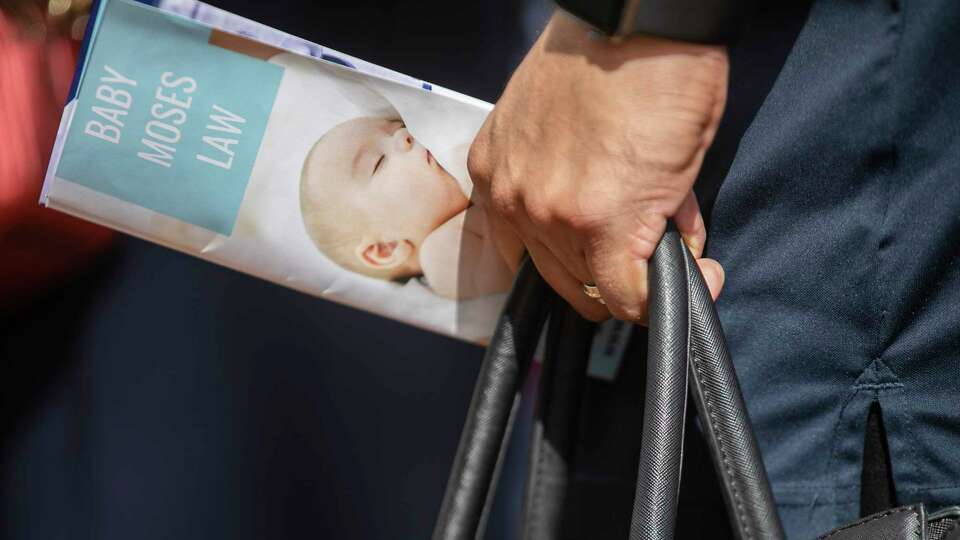 A person holds a pamphlet about Baby Moses Law during a press conference held outside City Hall in San Antonio, TX, on Sept. 2, 2022. The conference was held to publicly announce a proposal to create so-called 'baby boxes' where people can drop off infants anonymously, removing face-to-face interaction in an often difficult moment for parents.