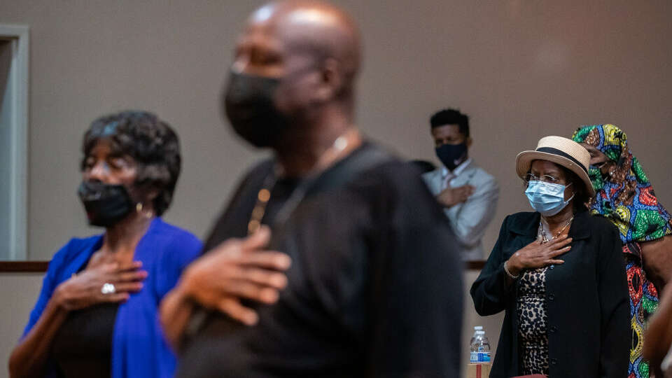 People hold their hand on their hearts as they participate in the first Slavery Remembrance Day commemorative ceremony at Greater Grace Houston, Friday, Aug. 20, 2021, in Houston.