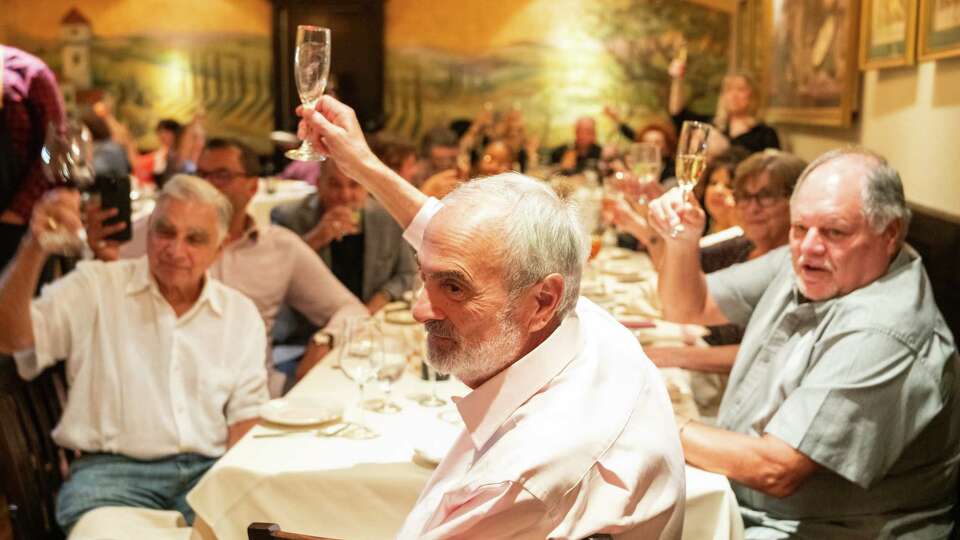 Damian Mandola, founder and former owner of Damian's Cucina Italiana, (center) raises his glass as friends and family give toasts to the longtime establishment during the final dinning service at restaurant, Saturday, Aug. 17, 2024, in Houston. After a four-decade run as one of Houston’s leading Italian restaurants, the Midtown institution closed its doors following series of challenges over the past few years from Hurricane Harvey, the COVID-19 pandemic and rising food costs.