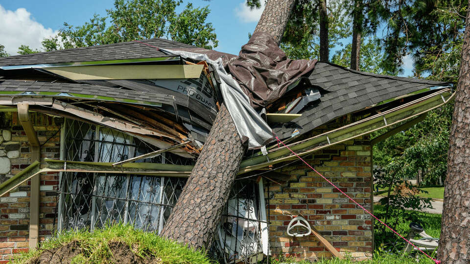 A fallen tree on the roof of a home in Meadowcreek Village in Houston, July 16.