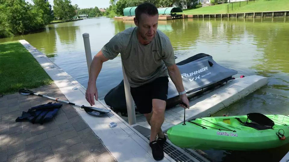 Blue Heron Bay resident Steve Smithers pulls his kayak back on shore at his home on Tuesday, Aug. 20, 2024 in Montgomery. In 2020, the water was between 6-8 feet, now due to the now-shallow water, Smithers can no longer use his jet skis or boat that he bought for the waterfront property.