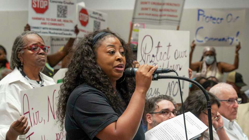 Citizens hold signs in the background as Erika Johnson makes a comment opposing the proposed Julpit Inc. concrete crushing facility Tuesday, Aug 20, 2024 during a forum at Restoration City Life Center in Rosharon.