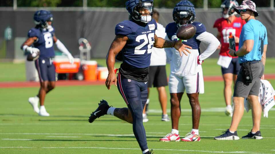 Houston Texans running back Joe Mixon (28) flips the ball after taking a handoff during an NFL training camp Wednesday, Aug. 21, 2024, in Houston.