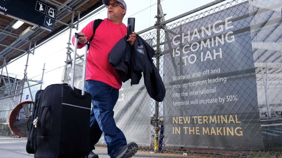 A man make his way to the temporary passenger pickup area for Terminal E at George Bush Intercontinental Airport, Tuesday, Aug. 27, 2024, in Houston. The airport is undergoing the second of its three-phase, $1.458 billion capital improvement program for the international terminal scheduled to be completed in 2025.