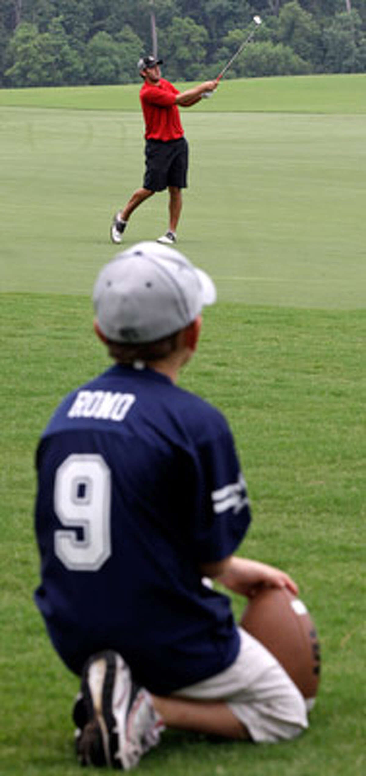 John Diggins, 8, watches Tony Romo hit an approach shot on the 18th hole during qualifying for the U.S. Open.