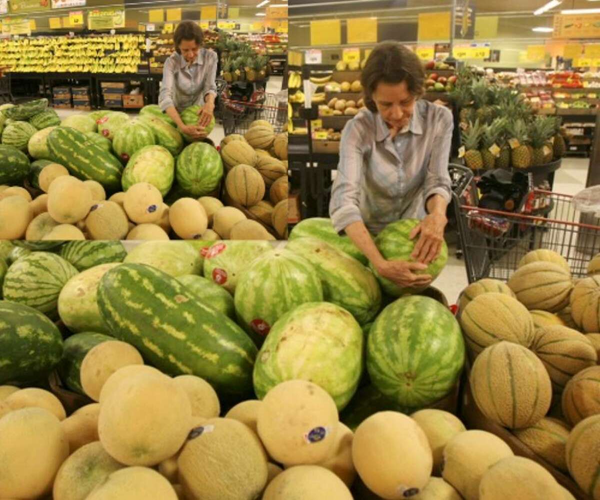 Kathy Labatt chooses a watermelon at H-E-B. Prices for consumers are down at many stores this year.
