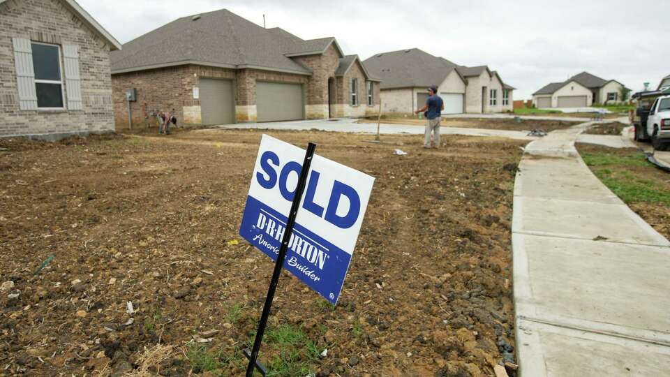 A sold sign sits out front of a home as men work Saturday, Aug. 31, 2024, at the River Ranch subdivision in Dayton.