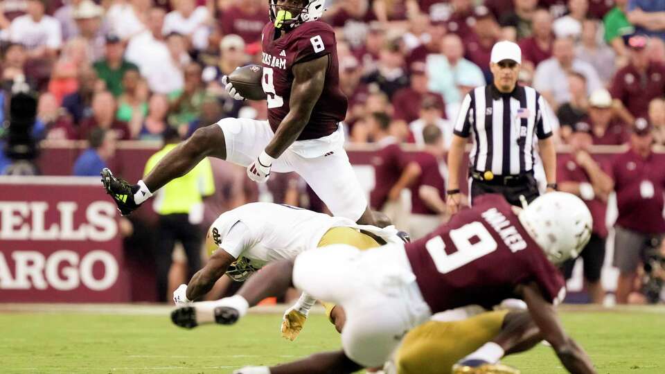 Texas A&M Aggies running back Le'Veon Moss (8) leaps over Notre Dame Fighting Irish safety Jordan Clark (1) during the first quarter of a non-conference college football game at Kyle Field, Saturday, Aug. 31, 2024, in College Station.