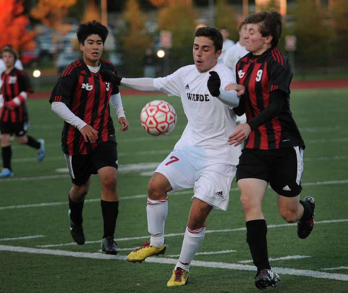 Fairfield Warde's Jason Correia plays the ball between New Canaan defenders Adam Braccio, left, and Jack O'Rourke during the Mustangs' 3-0 victory in the FCIAC boys soccer semifinals at Fairfield Ludlowe High School on Monday, November 1, 2010.