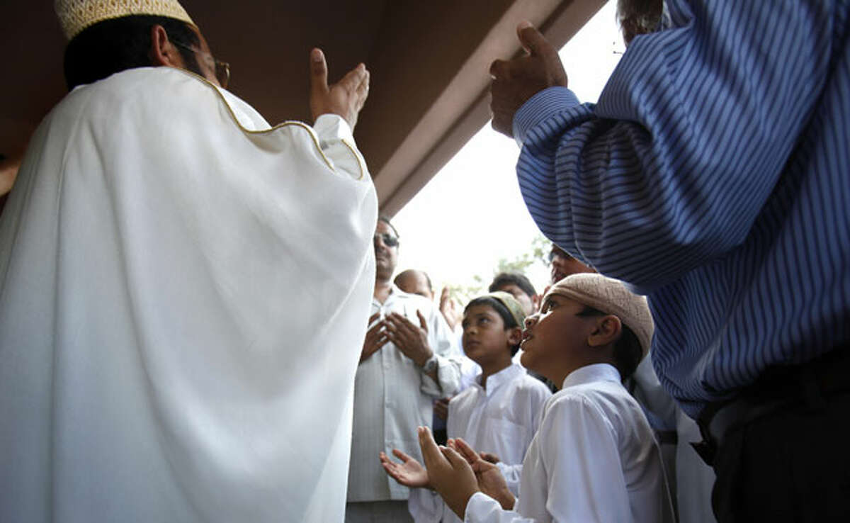 Led by Imam Ameen Aziz (left), men and boys pray during the opening of the new Al-Madinah Mosque, the centerpiece of the Muslim Children Education and Civic Center on the Northwest Side, on Aug. 13.