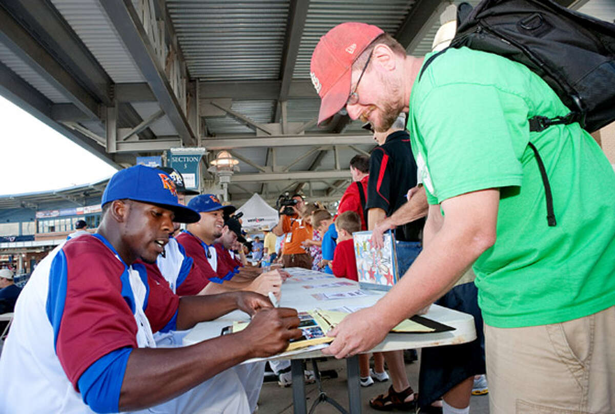 Midland RockHounds outfielder Archie Gilbert autographs a baseball card for Jeff Beg at the Texas League All-Star Game.