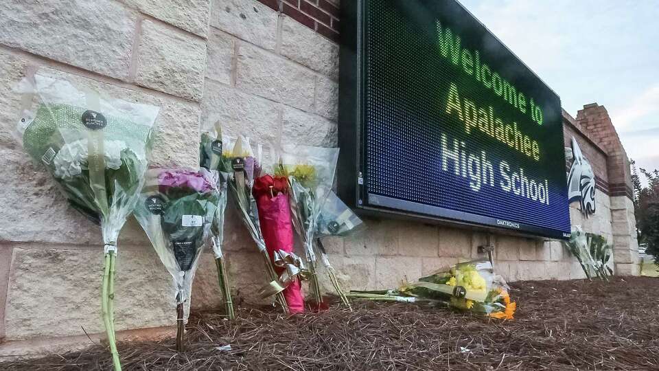 Flowers are placed at the foot of the welcome sign to Apalachee High School for a makeshift memorial on Sept. 5, 2024.