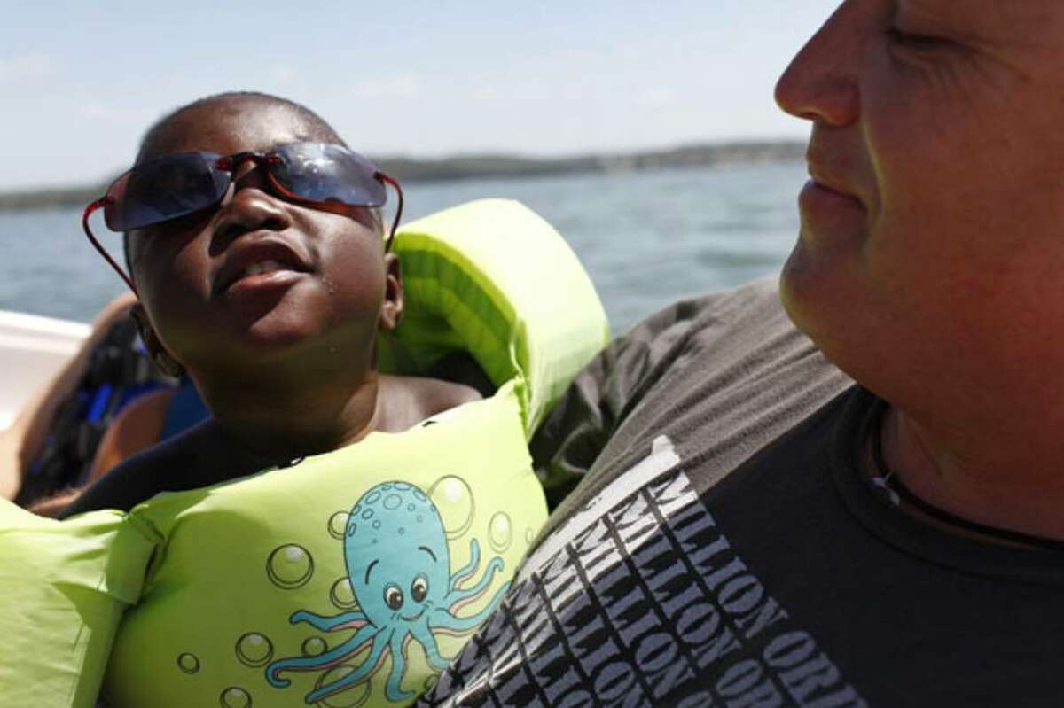 Kiefer Patterson, 2, with his adoptive father, Matt Patterson, on a boat during a gathering of Haitian children now living in the San Antonio area at the home of John Leininger on Lake LBJ in Marble Falls.
